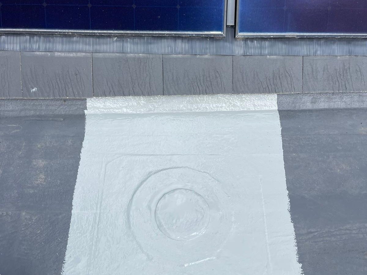 Liquid waterproofing repair worked around a flat roof outlet during maintenance