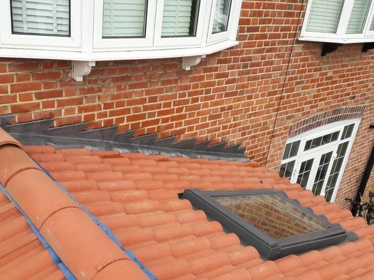 Hand-dressed lead step flashing to brickwork on a finished clay tile roof